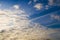 Aircraft condensation contrails in the blue sky inbetween some clouds