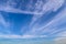 Aircraft condensation contrails in the blue sky inbetween some clouds