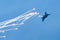 Aircraft fighter flies and shoots heat guns in the blue sky.