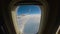 Aircraft flies over the clouds, view through the window to the wing of an passenger airplane