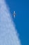Aircraft flies vertical upward skyward like a rocket on a diagonal blue sky background with diagonal clouds. To the