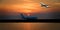 Aircraft in flight with cirrus cloud in orangge sky. Australia.