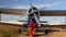 Aircraft ground crew starting the engine of an old russian biplane by spinning the propeller