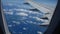 Aircraft porthole and view of the wing and clouds. Travel to other countries