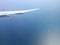 Aircraft wing above calm sea with still water and ships sealing.