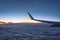 Aircraft wing view from airplane with cloudscape sky after sunset