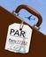 An airline luggage tag hangs from a suitcase or briefcase as an airliner flies high above in the background. This travel tag is fo