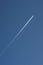 Airliner flying through the dark blue sky with a contrail stretching out behind it