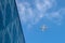Airplan leaves a trail in the blue sky. Airliner is takking off over the building. White cloud in the blue sky in which