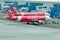 Airplane by Airasia airline is towed to a parking lot with aircraft towing tractors.