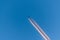 Airplane in a blue cloudless sky with colored colorful contrails without clouds during sunset and golden hour, Germany
