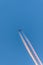 Airplane in a blue cloudless sky with colored colorful contrails without clouds during sunset and golden hour, Germany