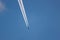 Airplane on a blue sky with its white contrails