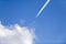 An airplane with contrails and clouds in the blue sky