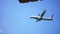 Airplane flies through the blue sky and hides behind the metallic roof