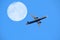 airplane flight against full moon and blue sky, aviation and travel concept