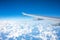 Airplane flying above the summer clouds, aerial wing view