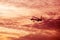 Airplane flying away in awesome cloudy sunset sky