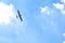 Airplane flying in the blue sky on background of white clouds, rear view. Twin-engine commercial plane during the turn, vacation