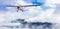 Airplane flying over the mountain landscape during cloudy day.