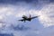 Airplane flying under beautiful evening clouds, front view