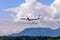 Airplane flying under the clouds over the trees