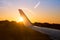 Airplane jet wing at sunset with golden sunlight