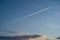 An airplane leaves a white vapor line on a beautiful sunset sky. Blue sky, dark clouds, orange sunset