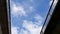 Airplane passing above between two railing against partly cloud sky.