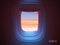 Airplane porthole in the evening ambient atmosphere with clouds sunset visible through window. In pink blue color scheme