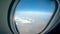 Airplane porthole with the land and the sky seen from it