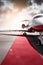 Airplane with red carpet on airport taxiway under bright blue sky