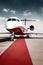 Airplane with red carpet on airport taxiway under bright blue sky