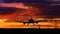Airplane silhouette landing on red sky background