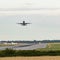 An airplane takes off as others come into land in an aircraft landing queue behind, with other planes waiting next to the runway