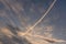 Airplane white pink condensation trail also known as chemtrails in conspiracy theory painted diagonally over clear morning sky