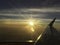Airplane window focus with sun set on horizon cloud sky through