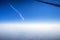 Airplane window view showing wing of a plane flying at sunrise