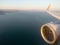 Airplane wing with engine out of window. Flight over sea coastline on sunrise. Airplane porthole view. Blurred image