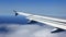 Airplane wing flying over clouds in blue sky