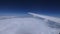 Airplane wing moving above white clouds under blue sky