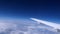 Airplane wing moving above white clouds under blue sky