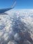 Airplane wing over clouds and sunny blue sky.