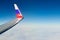 Airplane wing with Russian flag colors over clouds aerial view from aircraft window, parts problem