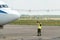 An airport employee in special clothes and headphones conducts pre-flight testing of the aircraft. The plane is on the runway. The