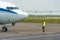 An airport employee in special clothes and headphones conducts pre-flight testing of the aircraft. The plane is on the runway. The