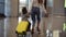 Airport terminal, young unrecognizable mother riding her cute daughter on a small yellow suitcase. Mom with yellow