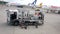 An airport worker connects a pump to a fuel tank and pulls out a fueling hose for an airplane in an airport terminal parking lot