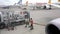 An airport worker connects a pump to a fuel tank and pulls out a fueling hose for an airplane in an airport terminal parking lot