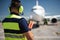 Airport worker in headphones looking at passenger plane